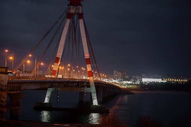 Un gran puente de automóviles en el que los coches circulan por la noche. Un puente con grandes columnas e iluminación.