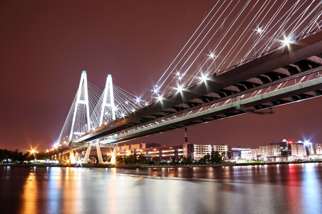 Gran puente de cables sobre el río por la noche con una iluminación brillante y colorida