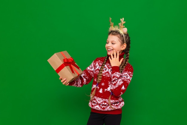 Un gran regalo para Navidad en manos de una niña, un niño con un suéter navideño con una imagen de ciervo