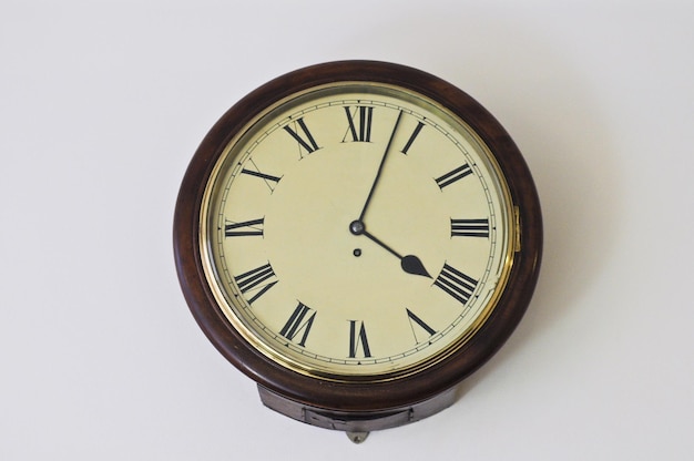 Gran reloj antiguo vintage con la hora a las 4 horas y 3 minutos en la pared blanca