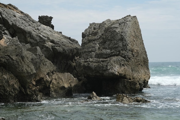 gran roca al borde del océano. playa rocosa con grandes olas y agua clara. playa en el karst.