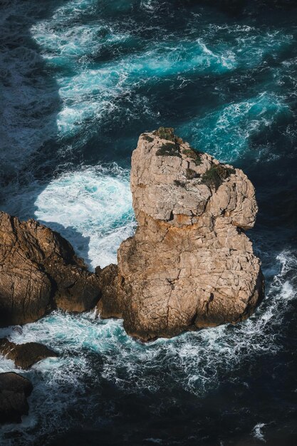 Foto una gran roca está en el océano con el océano en el fondo