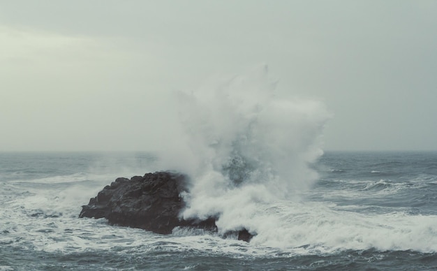 Foto gran rocha y salpicaduras de agua en la foto del paisaje de la tormenta