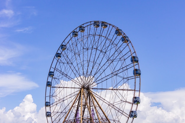 Gran rueda de la fortuna atraktsion en el fondo de un hermoso cielo azul con nubes