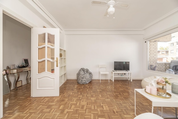 Gran salón de un apartamento con unos muebles blancos y puertas de acceso de cristal lacado en blanco.