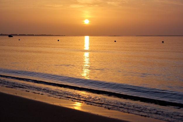 Gran sol amarillo poniéndose sobre la superficie del mar.