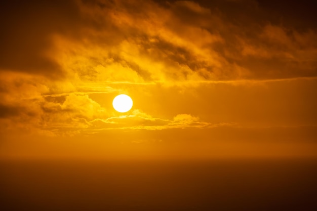 Gran sol asomándose a través de las nubes en un dorado atardecer sobre el mar Asturias España