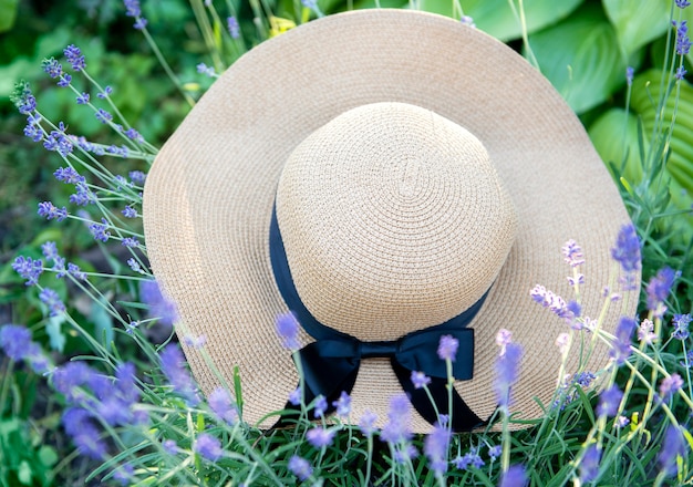Gran sombrero de paja en los arbustos de lavanda. Concepto de verano romántico.