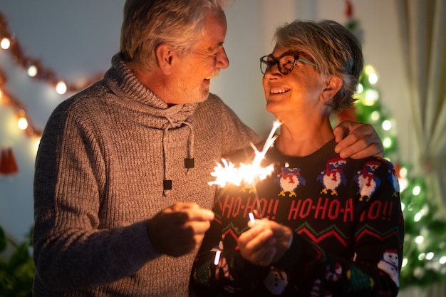 Una gran sonrisa entre una esposa mayor y un esposo que celebran la Navidad con chispas.