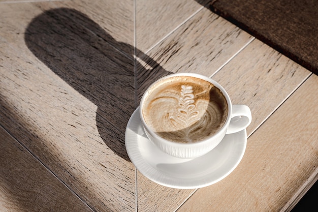 Gran taza blanca de capuchino con arte en mesa de madera