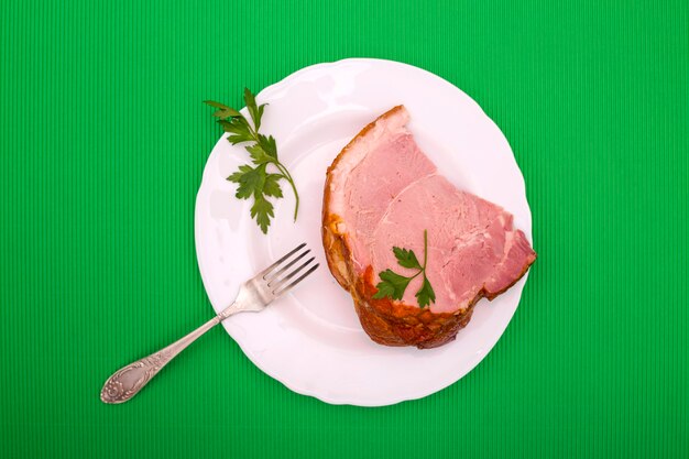 Un gran trozo de jamón de cerdo fresco en un plato sobre un fondo verde