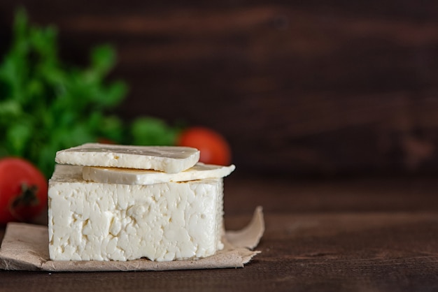 Foto gran trozo de queso feta sobre mesa de madera oscura. enfoque selectivo