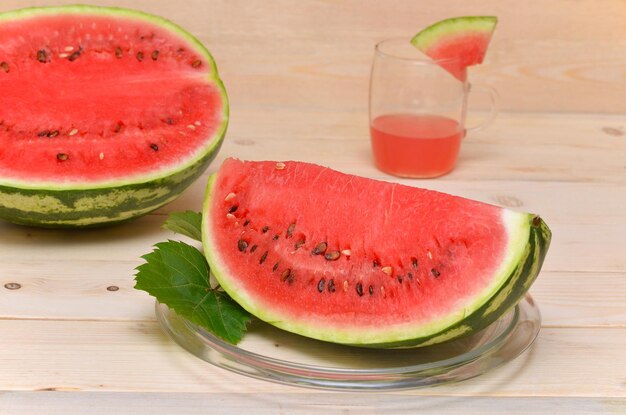 Un gran trozo de sandía y un vaso de jugo en el fondo