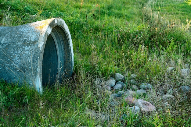 Una gran tubería de hormigón para desviar el río por debajo de la carretera Fugas de agua sucia de grandes tuberías de hormigón Aguas residuales sucias de la tubería contaminación ambiental Problema ambiental