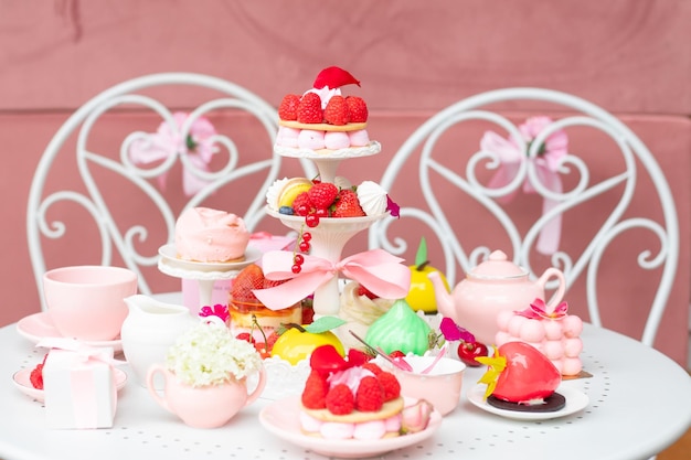 Gran variedad de golosinas de postre de azúcar rosa en la mesa blanca en la cafetería o en la tienda de dulces Celebración navideña con comida sabrosa