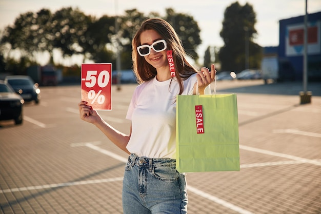 Foto gran venta una mujer hermosa con ropa casual está sosteniendo bolsas de compras al aire libre