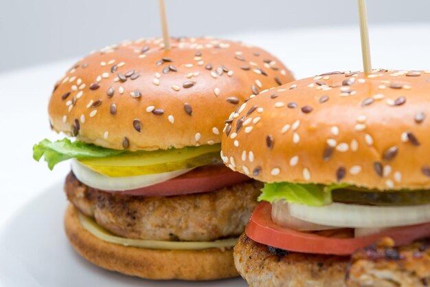 Una gran vista de una gran hamburguesa con tomates cebolla pepino en un plato blanco