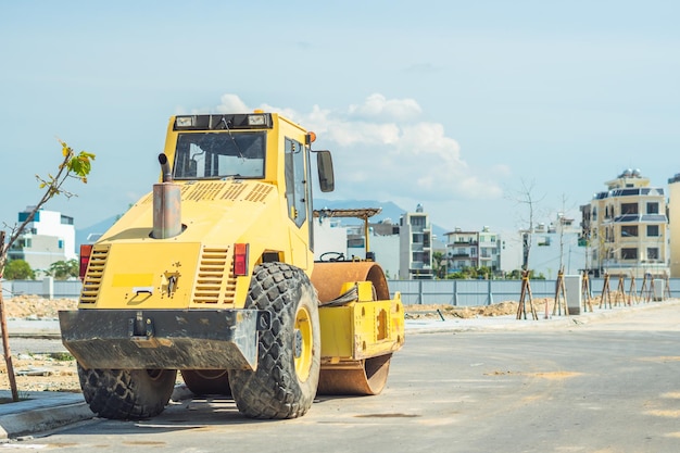 Gran vista de los grandes rodillos amarillos que trabajan en el nuevo y moderno sitio de construcción de carreteras del distrito de edificios de varios pisos bajo un cielo azul Industria de la construcción civil