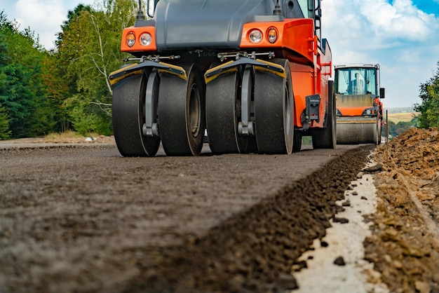 Gran vista de los rodillos de camino que trabajan en el nuevo sitio de construcción de carreteras Enfoque selectivo en la reparación de carreteras Primer plano