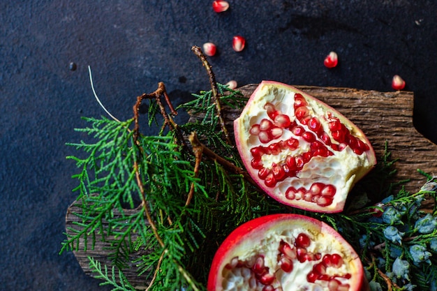 Granada dulce de frutos rojos sobre la mesa y una ramita de árbol de navidad verde