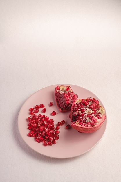 Granada fresca dulce sabrosa pelada con semillas rojas en placa rosa