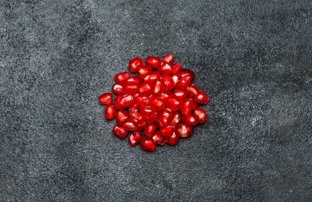 Foto granada y semillas en mesa de hormigón oscuro