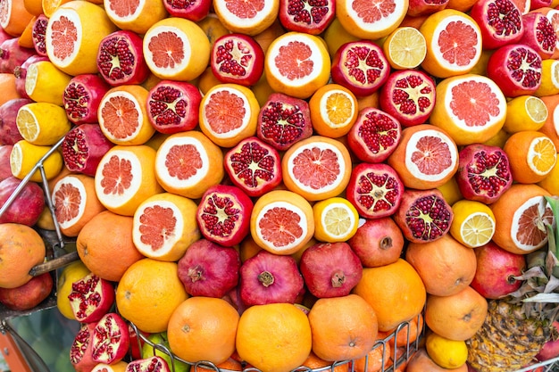 Granadas maduras y jugosas medio peladas, naranjas listas para ser exprimidas para jugo fresco.