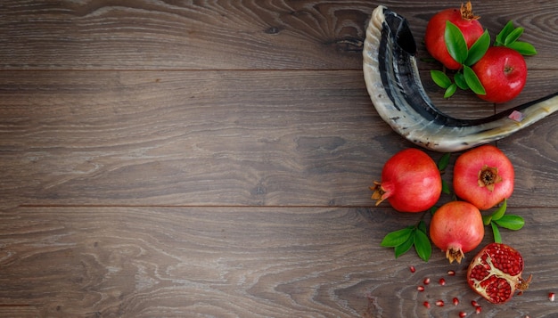 Granadas manzanas rojas cuerno de shofar sobre una mesa de madera el concepto del año nuevo judío Rosh Hashaná Vista superior