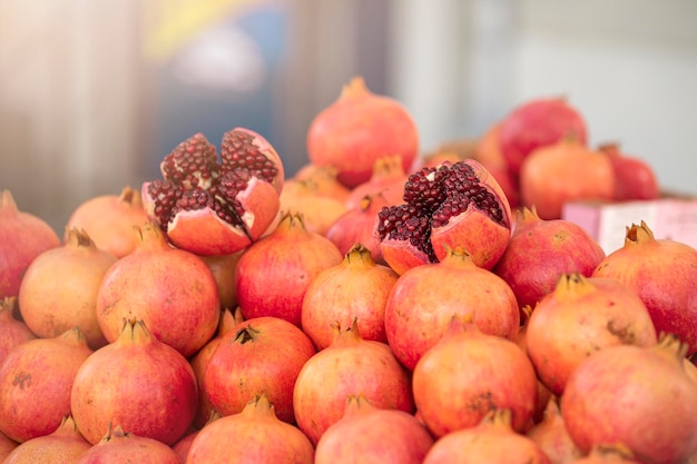 Granadas en el mercado en el mostrador granadas maduras frescas apiladas cortadas en pedazos agrietados po