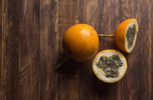 Granadilla doce ou maracujá grenadia. Inteiro e cortado ao meio frutas exóticas na placa de madeira. Copiar espaço