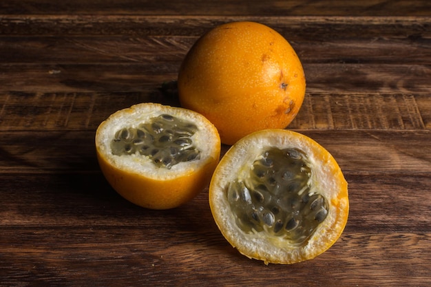 Foto granadilla doce ou maracujá grenadia. inteiro e cortado ao meio frutas exóticas na placa de madeira