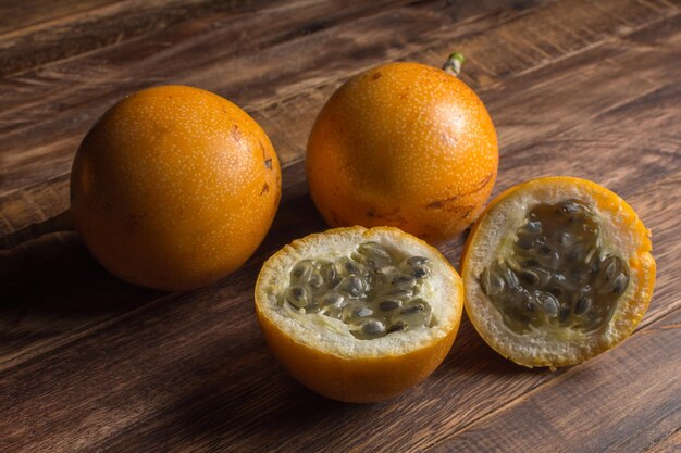 Granadilla dulce o maracuyá granadina. Frutas exóticas enteras y cortadas a la mitad sobre tabla de madera