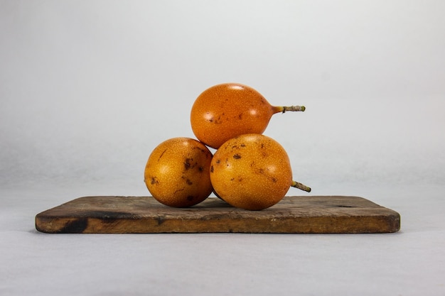 Granadilla tres frutas peruanas de piel dura sobre un plato de porcelana y tablero de madera