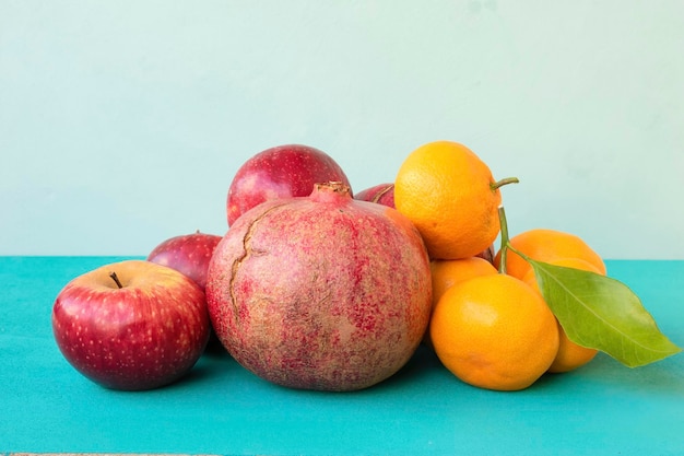 Foto granatäpfel, äpfel und mandarinen auf türkisfarbenem hintergrund. reife früchte