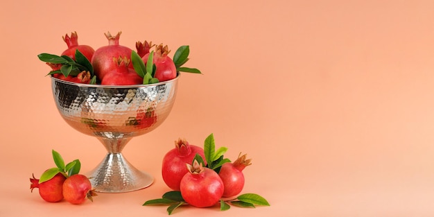 Foto granatäpfel in einer silbernen schüssel auf einem korallenroten hintergrund rosh hashanah jüdisches neujahrsfeiertagskonzept