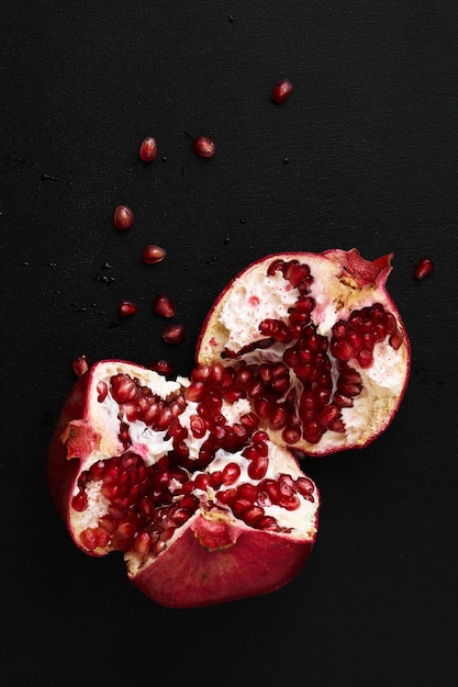 Granatapfel auf schwarzem Hintergrund halbieren. Nahaufnahme