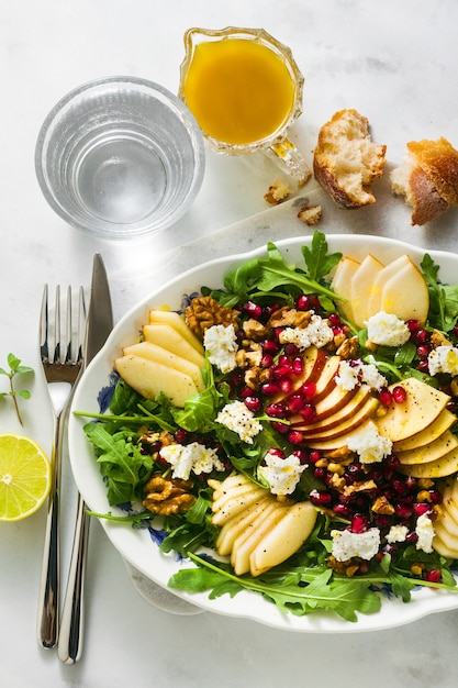 Granatapfel-Birnen-Grün-Salat mit Ingwer-Dressing auf weißem Marmor. gesundes Frühstück oder Mittagessen