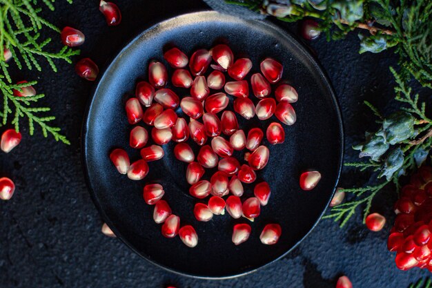 Granatapfel rote Frucht süß auf dem Tisch und ein Zweig des grünen Weihnachtsbaumes