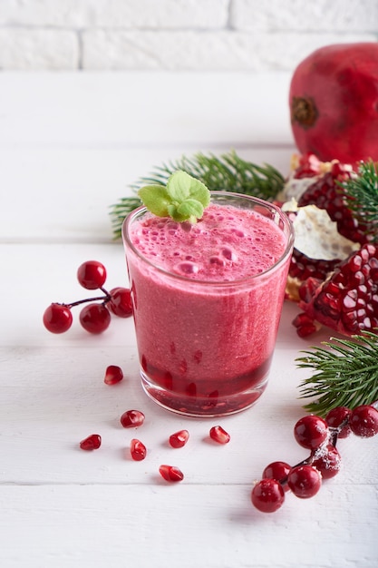 Granatapfel Smoothie in einem Glas mit Tannenzweigen und Weihnachtsdekoration