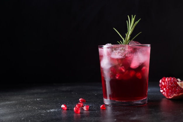 Granatapfel-weihnachtscocktail mit rosmarin, champagner, club-soda auf schwarzem tisch. nahaufnahme.