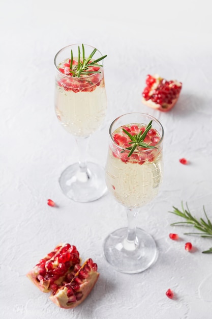 Granatapfel-Weihnachtscocktail mit Rosmarin, Sekt auf weißer Tabelle. Weihnachtsfeiertagsgetränk.