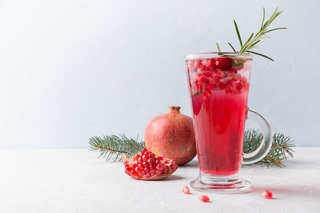 Granatapfel-Weihnachtscocktail mit Sekt, garniert mit Rosmarinzweig