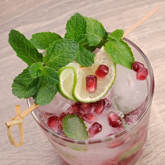 Granatapfelcocktail mit Limettenscheiben, Minze und Eis