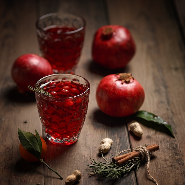 Granatapfelsaft mit Granatäpfeln und Trockenfrüchten auf einem Holztisch. Landhausstil.