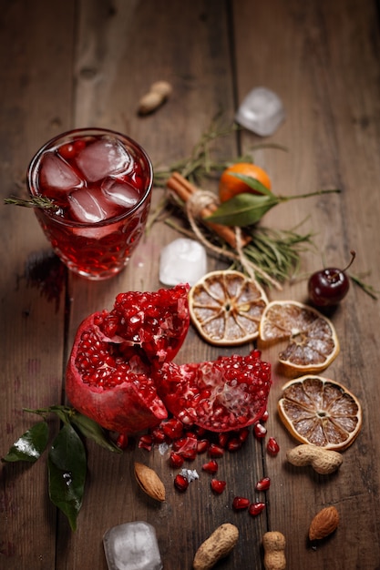 Granatapfelsaft mit Granatäpfeln und Trockenfrüchten auf einem Holztisch. Landhausstil.