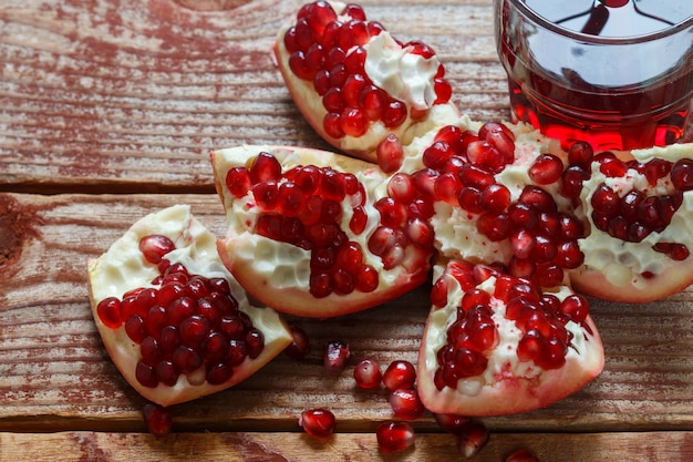 Granatapfelsamen und Granatapfelsaft im Glas auf altem Holztisch. Tiefenschärfe