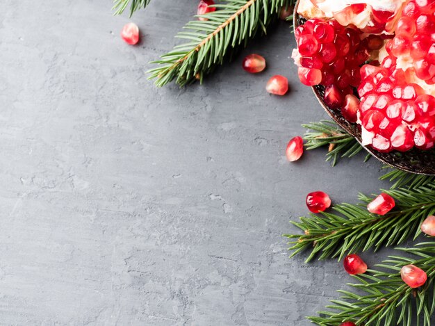 Granate rojo jugoso pelado en un plato vintage en árbol de Navidad