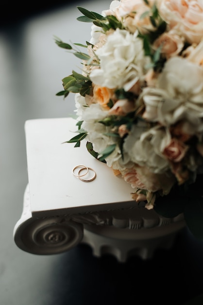 Foto grande buquê de casamento e anéis em cima da mesa