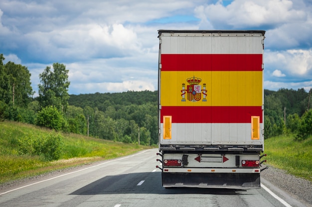 Grande caminhão com a bandeira nacional da Espanha, movendo-se na estrada