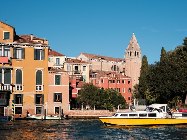 Grande Canal em Veneza, Itália. Barco de vaporetto de passageiros e edifícios históricos com a torre do sino da igreja, campanário. Transporte marítimo veneziano de passageiros, logotipos removidos para uso comercial.